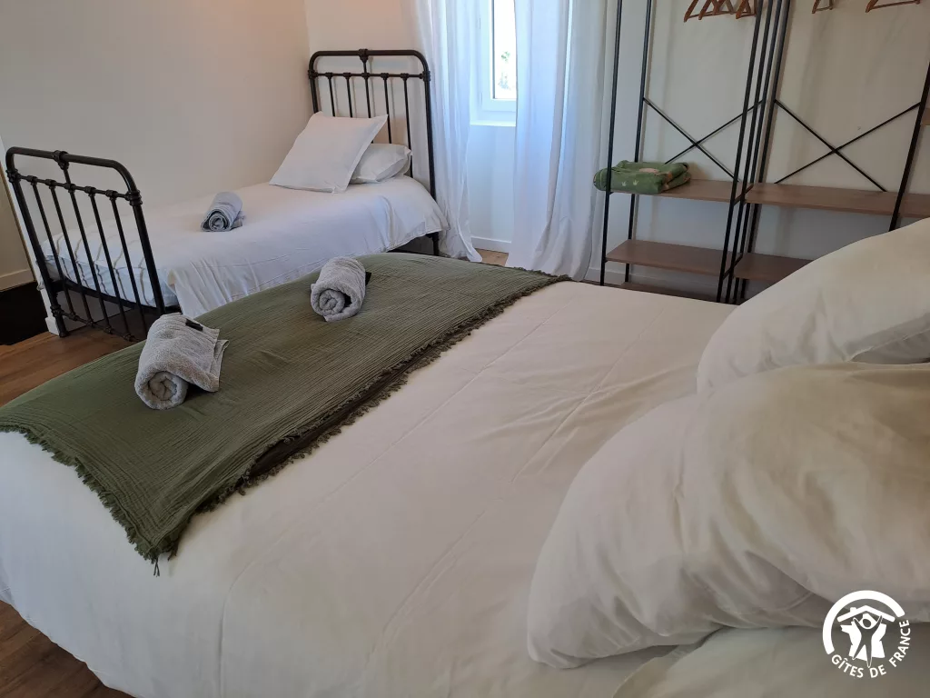 Chambre avec literie blanche et plaid vert