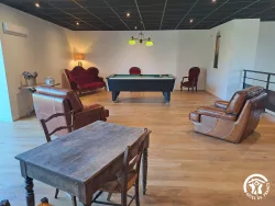 Salle de jeux avec billard et canapés au Domaine des Hirondelles