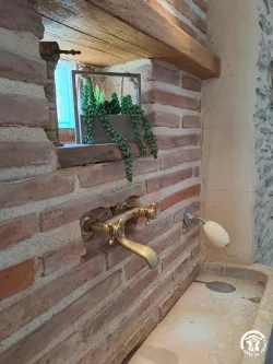 Robinet doré sur mur en briques au Domaine des Hirondelles