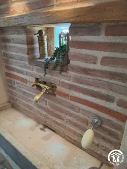 Robinet doré sur mur en briques au Domaine des Hirondelles