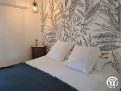 Chambre avec linge de lit et papier peint feuillage au Domaine des Hirondelles