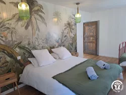 Chambre avec papier peint tropical et lit double au Domaine des Hirondelles