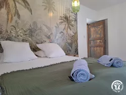 Chambre avec papier peint tropical et lit double au Domaine des Hirondelles