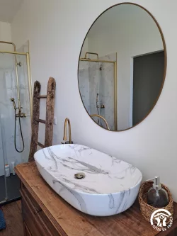 Salle de bain avec miroir rond et douche au Domaine des Hirondelles