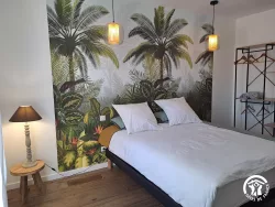 Lit double devant papier peint tropical au Domaine des Hirondelles