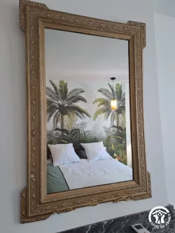 Miroir doré et papier peint palmiers au Domaine des Hirondelles