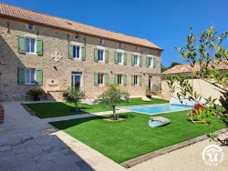Façade en pierre, pelouse et piscine au Domaine des Hirondelles