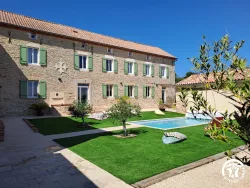 Façade en pierre, pelouse et piscine au Domaine des Hirondelles