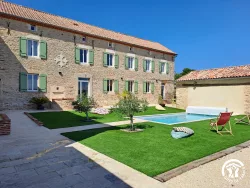 Façade en pierre, pelouse et piscine au Domaine des Hirondelles