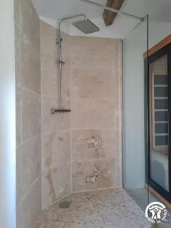 Douche et mur en pierre claire au Domaine des Hirondelles