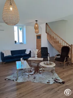 Salon avec canapé bleu et escalier en bois au Domaine des Hirondelles