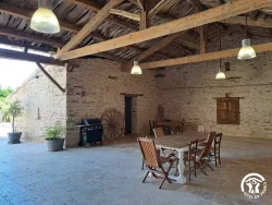 Grande salle en pierre avec poutres au Domaine des Hirondelles