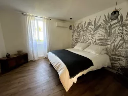 Chambre avec lit double et papier peint feuillage au Domaine des Hirondelles