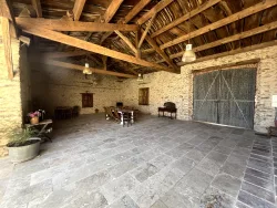 Grande salle en pierre avec charpente apparente et grande porte au Domaine des Hirondelles
