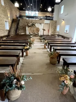 Bancs alignés pour une cérémonie dans la grande salle au Domaine des Hirondelles
