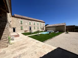Façade en pierre, pelouse et piscine au Domaine des Hirondelles